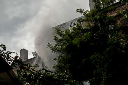 Fire in a residential five-story building. Firefighters in the basket on the fire escape assess the danger of the situation.の写真素材