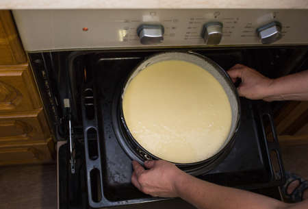 Step by step the process of making sour cream pie dough. Female hands place ready-made raw dough in a prepared baking dish into a hot oven. Baking concept.の写真素材