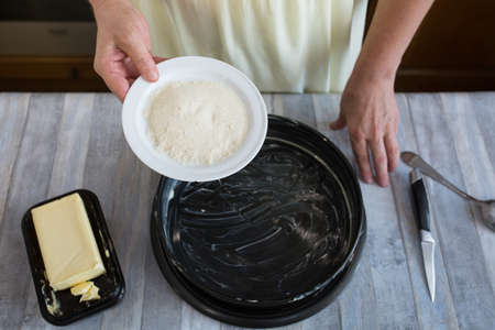 Step by step the process of making sour cream pie dough. Female hands prepare a baking dish, grease with butter and sprinkle with semolina. Baking concept.の写真素材