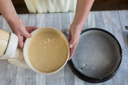 Step by step the process of making sour cream pie dough. Female hands pour the finished raw dough into a prepared baking dish. Baking concept.の写真素材