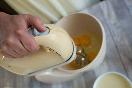 Step by step the process of making sour cream pie dough. The mixer beats the eggs in the dough bowl. Baking concept.の写真素材