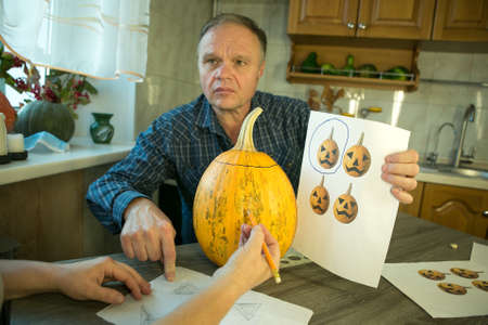 Making Jack O'Lantern at home. The process of creating a Jack O'Lantern theme template. A man and a woman are preparing a pumpkin for carving.の写真素材