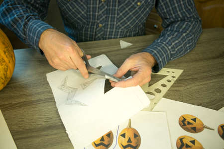 Making Jack O'Lantern at home. Jack O'Lantern thread template creation process. The man prepares the...