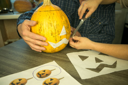 Making Jack O'Lantern at home. The process of creating a Jack O'Lantern theme template. A man and a woman are preparing a pumpkin for carving.の写真素材