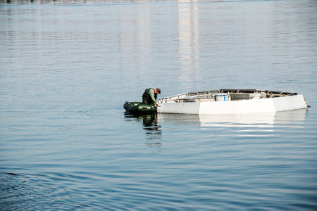 Dnepropetrovsk, Ukraine - 10.15.2021: Maintenance works of the city fountain. A municipal service worker delivers a tool for working on a rubber boat.のeditorial素材