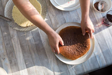 Step-by-step process of making a sour cream chocolate cake. Forming the cake. The chocolate cake is broken into pieces and smeared with sour cream. Baking concept.の写真素材