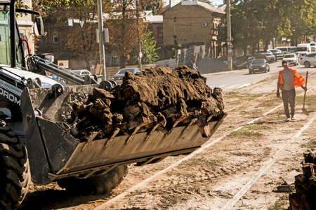 Dnepropetrovsk, Ukraine - 09.15.2021: Excavator, grader and workers remove debris after dismantling a tram stop. Works on tram tracks.のeditorial素材