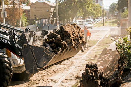 Dnepropetrovsk, Ukraine - 09.15.2021: Excavator, grader and workers remove debris after dismantling a tram stop. Works on tram tracks.のeditorial素材