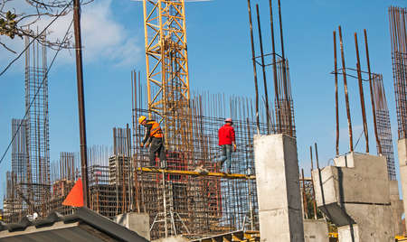Dnepropetrovsk, Ukraine - 10.12.2021: Workers prepare a reinforcing cage for pouring concrete columns for a residential building. Mounting. Construction cranes. Concrete structures.のeditorial素材