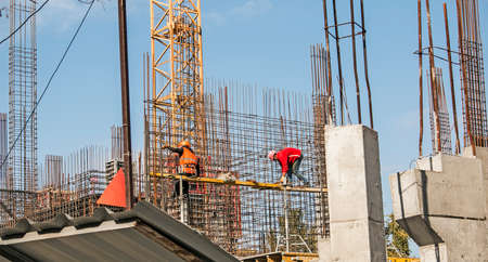 Dnepropetrovsk, Ukraine - 10.12.2021: Workers prepare a reinforcing cage for pouring concrete columns for a residential building. Mounting. Construction cranes. Concrete structures.のeditorial素材