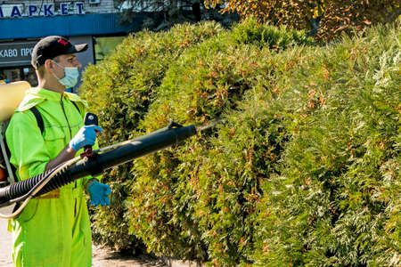 Dnepropetrovsk, Ukraine - 10.05.2021: An employee of the city municipal service sprays plants of the urban landscape.のeditorial素材
