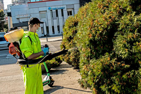Dnepropetrovsk, Ukraine - 10.05.2021: An employee of the city municipal service sprays plants of the urban landscape.のeditorial素材