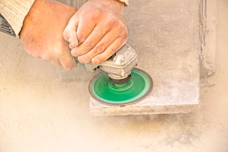 A man polishes a granite slab with a grinder. Work on stone with an angle grinder. A worker polishes...