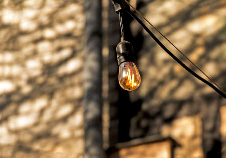 Background image of an outdoor lamp, focus on a classic light bulb with wiring. Copy space.の写真素材