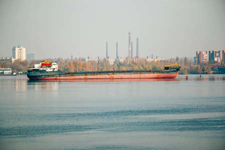 Dnepropetrovsk, Ukraine - 10.28.2021: An articulated tug and bulk barge transport sand and construction materials along the river. A large barge sails along the wide Dnieper River. Transport industry. Landscape.のeditorial素材
