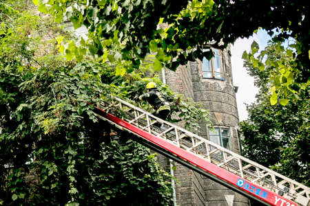 Dnepropetrovsk, Ukraine -09.20.2021: Fire on the top floor of a five-story building. A firefighter climbs the stairs and pulls a fire hose.のeditorial素材