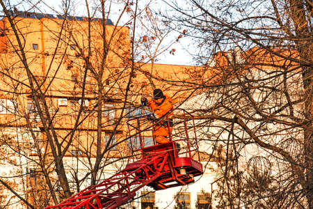 Dnepropetrovsk, Ukraine - 11.24.2021: Municipal workers on a truck crane decorate the city streets with Christmas lights. High-altitude work in sunny weather.のeditorial素材