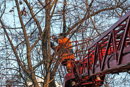 Municipal workers on a truck crane decorate the city streets with Christmas lights. High-altitude...