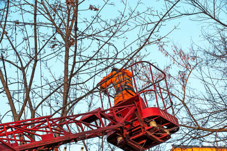 Municipal workers on a truck crane decorate the city streets with Christmas lights. High-altitude work in sunny weather.の写真素材