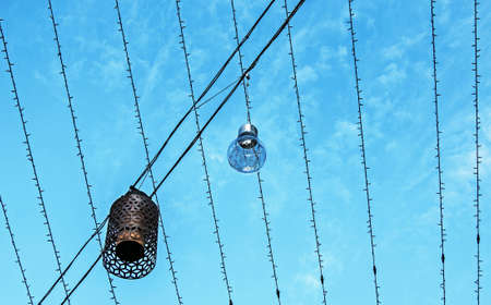 Suspended illumination on city streets. Christmas garlands on a background of blue sky. Detailing.