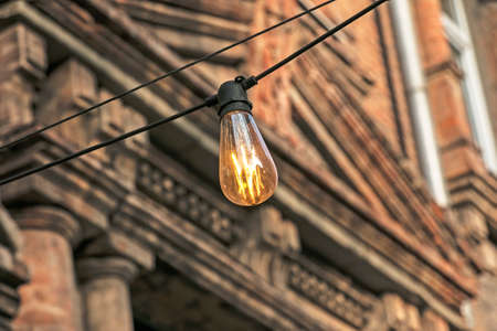 Background image of an outdoor lamp, focus on a classic light bulb with wiring. Copy space.の写真素材