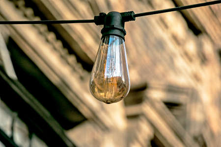 Background image of an outdoor lamp, focus on a classic light bulb with wiring. Copy space.