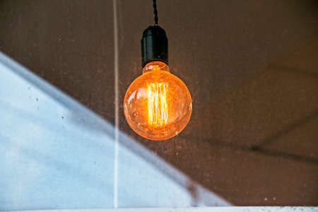 Background image of an outdoor lamp, focus on a classic light bulb with wiring. Copy space.の写真素材