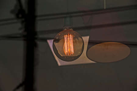 Background image of an outdoor lamp, focus on a classic light bulb with wiring. Copy space.の写真素材