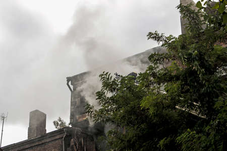 Fire on the top floor of a five-story building. Firefighters on the stairs watching the fire extinguish.の写真素材