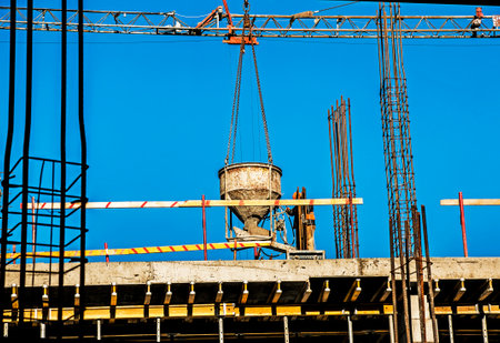 Construction worker at a construction site. Pouring concrete into the formwork.