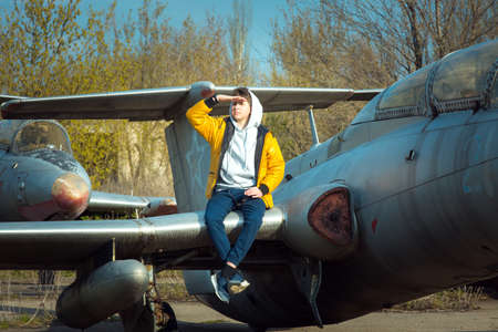 A young man in front of an old abandoned Soviet plane. The guy enjoys learning the old technique.