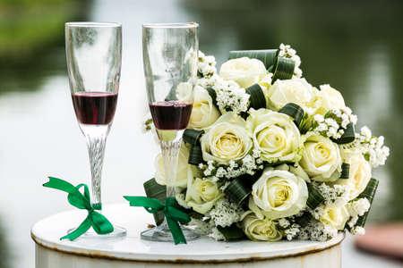 Red wine in glasses and yellow-white roses. summer holiday. wedding card. Invitation concept.の写真素材