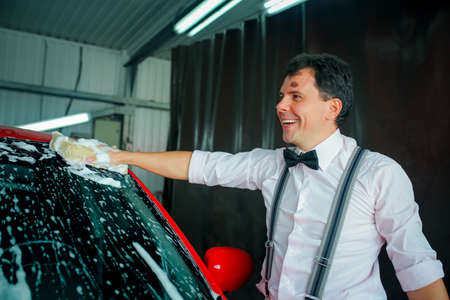 A young man washes a car at a car wash. Self service car wash.の写真素材