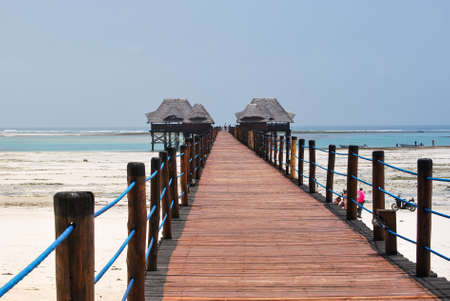 Wooden pier and thatched roofs on a tropical beach, Zanzibar island.の写真素材