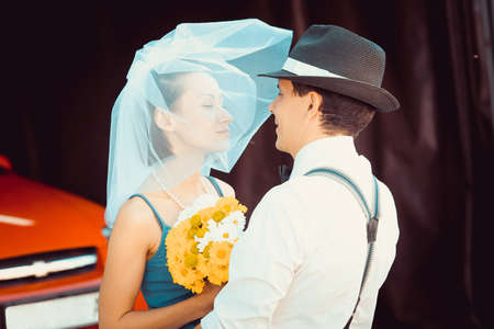 Portrait of a young couple in wedding attire celebrating their wedding anniversary. Smile, kiss, holding the bouquet together, love.の写真素材