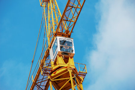 Dnepropetrovsk, Ukraine - 11.30.2021: High-rise construction crane with a long yellow boom against the blue sky. Emotions of a carpenter when lifting a load.のeditorial素材