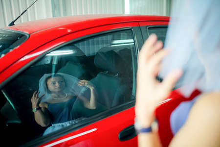 Reflection of a woman in a veil in the glass of a car at a car wash. wedding anniversary. Humor.の写真素材