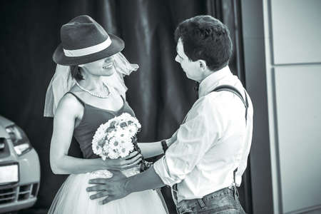 Portrait of a young couple in wedding attire celebrating their wedding anniversary in black and white. Smile, kiss, holding the bouquet together, love.の写真素材