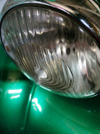 Close-up of a round headlight of a retro car in green.の写真素材