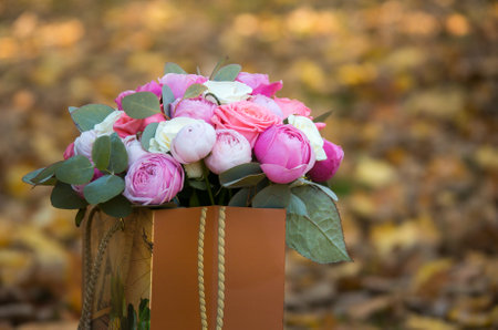 Wedding bouquet of white and pink rose flowers against blurry yellow autumn leaves. The concept of a holiday, wedding.の写真素材