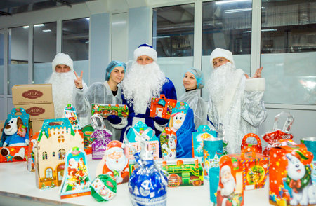 Dnepropetrovsk, Ukraine - 12.08.2017: Workers of a confectionery factory in Santa Claus costumes present New Year's products. On the boxes are the words in Russian and Ukrainian Happy New Year.のeditorial素材
