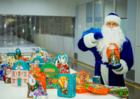Dnepropetrovsk, Ukraine - 12.08.2017: Workers of a confectionery factory in Santa Claus costumes present New Year's products. On the boxes are the words in Russian and Ukrainian Happy New Year.のeditorial素材