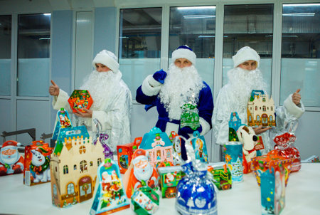 Dnepropetrovsk, Ukraine - 12.08.2017: Workers of a confectionery factory in Santa Claus costumes present New Year's products. On the boxes are the words in Russian and Ukrainian Happy New Year.のeditorial素材