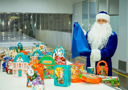 Dnepropetrovsk, Ukraine - 12.08.2017: Workers of a confectionery factory in Santa Claus costumes present New Year's products. On the boxes are the words in Russian and Ukrainian Happy New Year.のeditorial素材