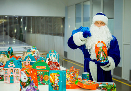 Dnepropetrovsk, Ukraine - 12.08.2017: Workers of a confectionery factory in Santa Claus costumes present New Year's products. On the boxes are the words in Russian and Ukrainian Happy New Year.のeditorial素材