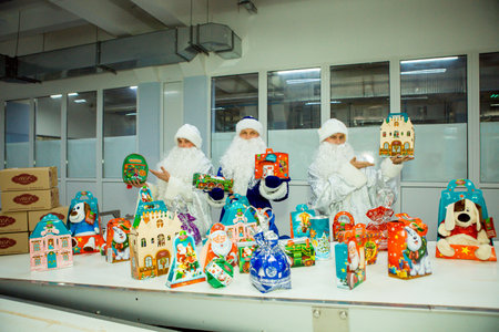 Dnepropetrovsk, Ukraine - 12.08.2017: Workers of a confectionery factory in Santa Claus costumes present New Year's products. On the boxes are the words in Russian and Ukrainian Happy New Year.のeditorial素材