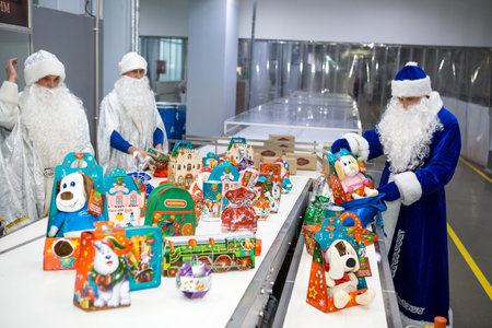 Dnepropetrovsk, Ukraine - 12.08.2017: Workers of a confectionery factory in Santa Claus costumes present New Year's products. On the boxes are the words in Russian and Ukrainian Happy New Year.のeditorial素材