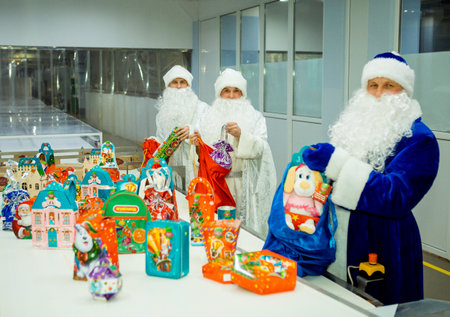 Dnepropetrovsk, Ukraine - 12.08.2017: Workers of a confectionery factory in Santa Claus costumes present New Year's products. On the boxes are the words in Russian and Ukrainian Happy New Year.のeditorial素材