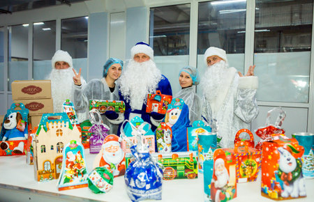 Dnepropetrovsk, Ukraine - 12.08.2017: Workers of a confectionery factory in Santa Claus costumes present New Year's products. On the boxes are the words in Russian and Ukrainian Happy New Year.のeditorial素材