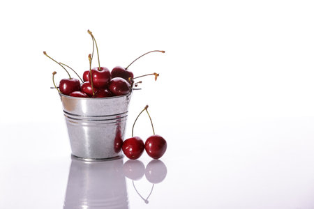 Juicy red fresh cherry berries in a bucket on a white background. Full depth of field.の写真素材